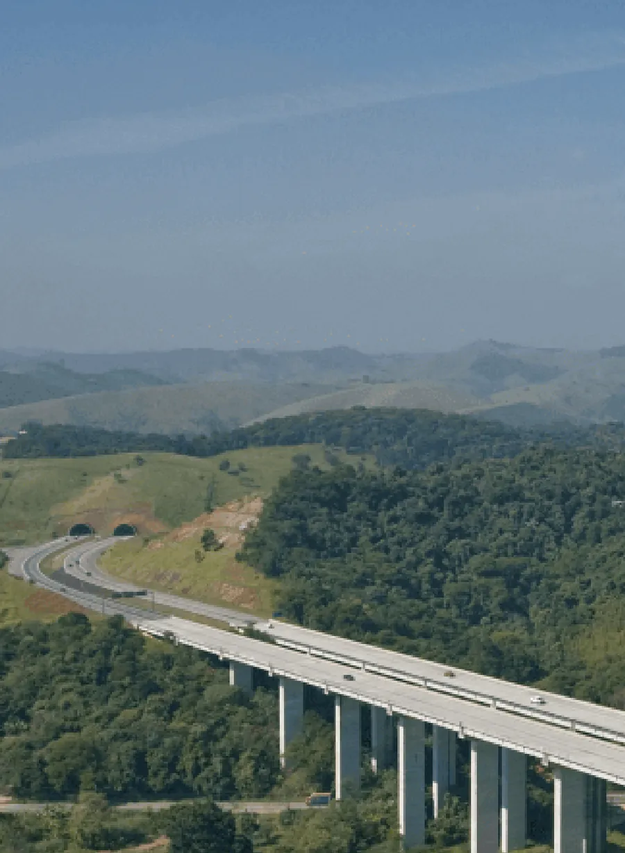Viaduto de concreto cruzando uma região de colinas cobertas por vegetação